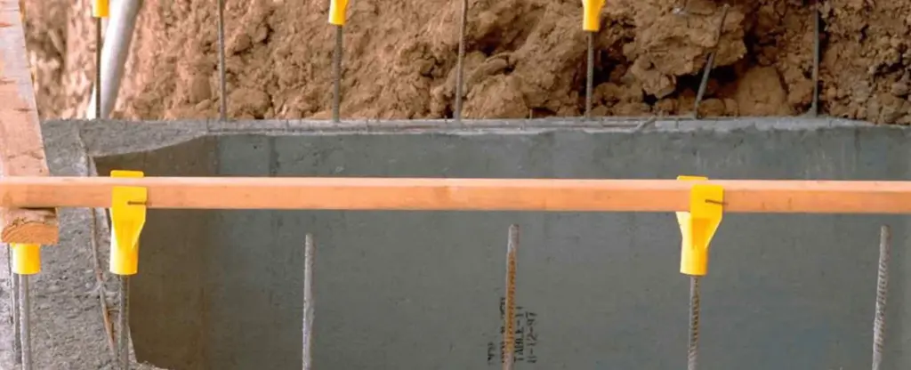 Coffrage de béton avec supports jaunes Carnie Cap de Plasti-Tom et barres d'armature.